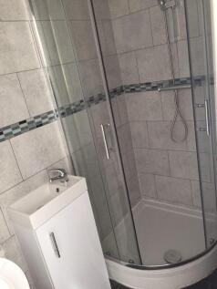 Modern bathroom featuring a curved glass shower...