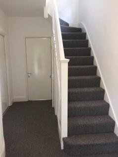 Bright and clean hallway featuring a carpeted s...