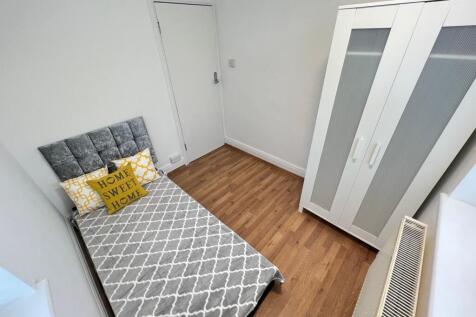 A neat and tidy single bedroom featuring a comf...