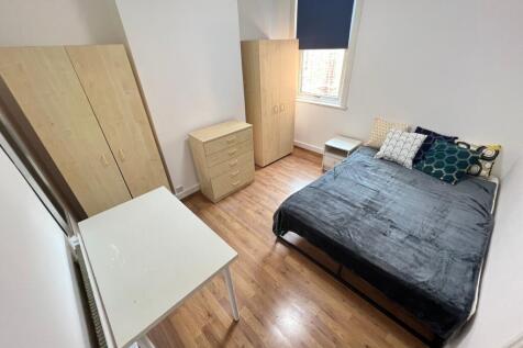 A cozy double bedroom featuring light wooden fl...