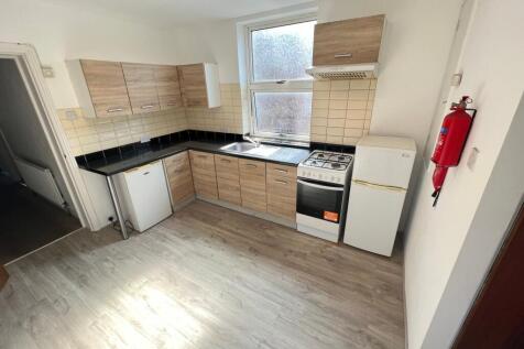 A modern kitchen featuring light wood cabinets,...