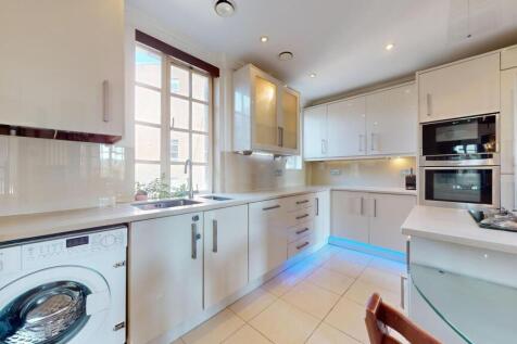 Modern kitchen featuring sleek white cabinetry,...