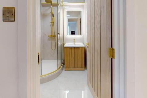 A sleek, modern bathroom featuring a curved gla...