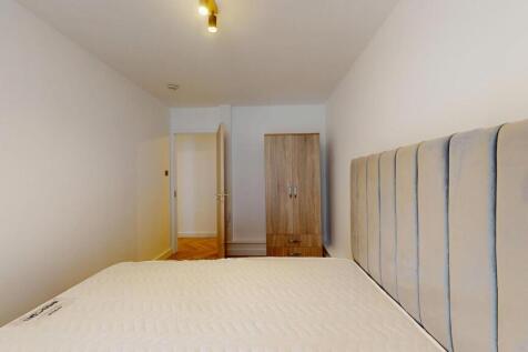 A neat and tidy single bedroom featuring a comf...