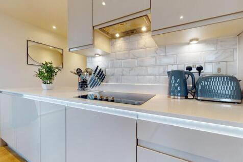 A sleek, modern kitchen featuring glossy white ...