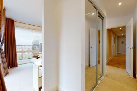 A bright and clean hallway with beige carpeting...