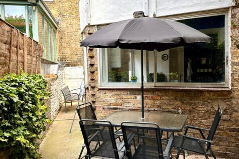 A charming outdoor garden area featuring a glas...