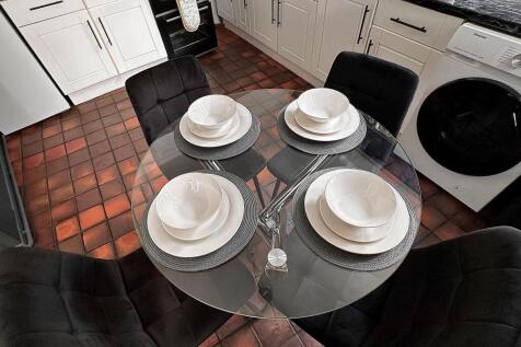 A modern kitchen featuring a sleek glass dining...