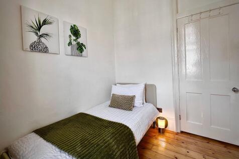 A cozy single bedroom featuring a neatly made b...