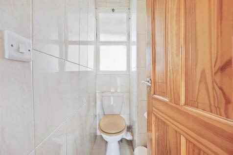 A bright and clean single toilet with white til...