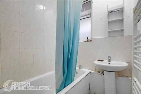 A compact bathroom featuring a white bathtub wi...