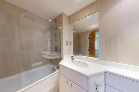 A modern bathroom featuring a bathtub with a gl...