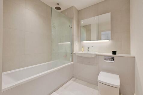 Modern bathroom with a sleek white bathtub, a s...