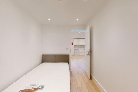A clean, minimalist single bedroom featuring a ...