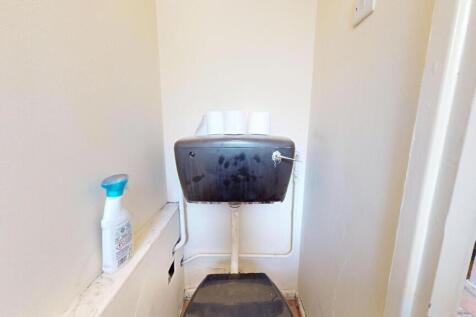A compact single toilet space featuring a black...