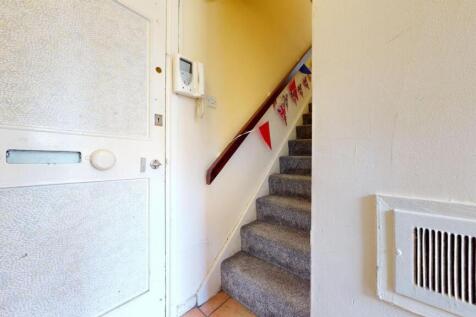 A cozy carpeted staircase with a wooden handrai...