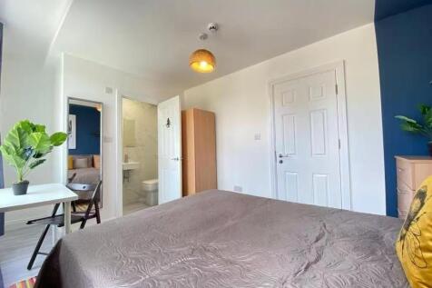 A spacious, well-lit master bedroom featuring a...