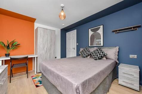 A modern, well-lit bedroom featuring a large be...