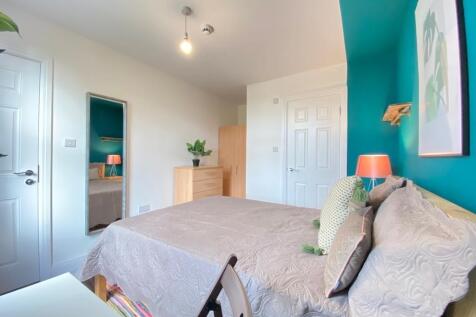 A cozy, well-lit bedroom featuring a comfortabl...