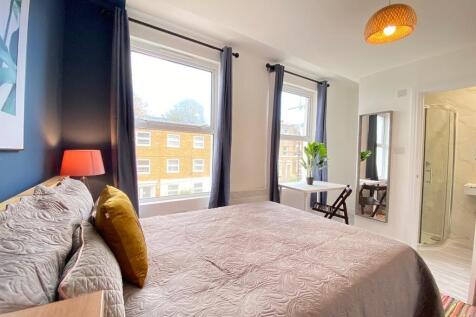 A bright, well-lit bedroom featuring a cozy bed...