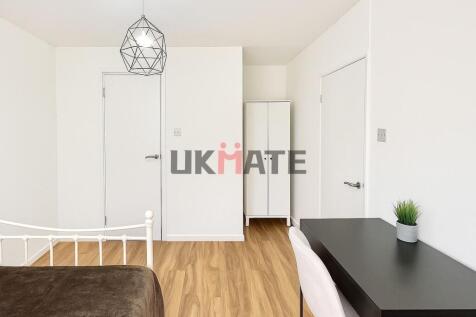 A bright and neat student bedroom featuring whi...