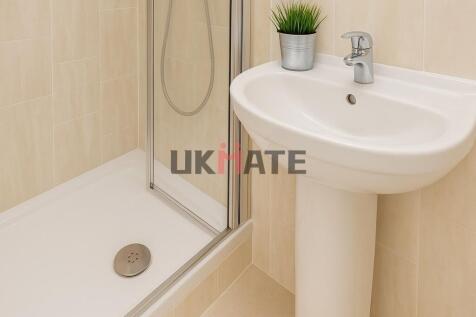 Clean and bright bathroom featuring a shower ar...