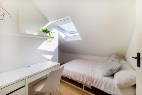 A bright, cozy bedroom featuring a comfortable ...