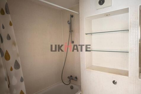 A standard bathroom featuring a bathtub with a ...