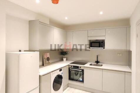 Modern and sleek kitchen with white cabinetry, ...
