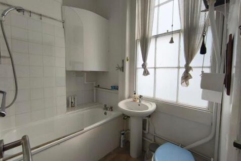 A compact bathroom featuring a bathtub with a s...