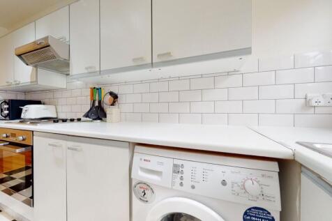 Bright and clean kitchen featuring white cabine...