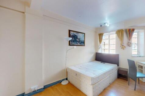 A compact bedroom featuring a single bed, a sid...