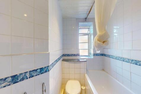 Bright and functional bathroom with white tiled...