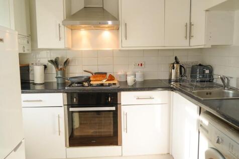 Bright and modern kitchen featuring white cabin...