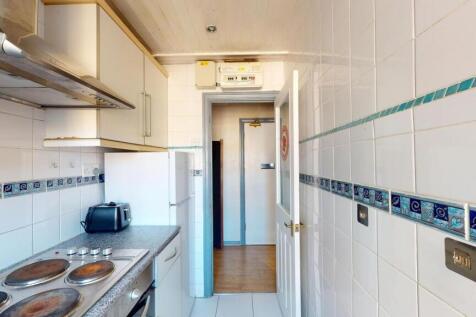 A functional and tidy kitchen with white tiled ...