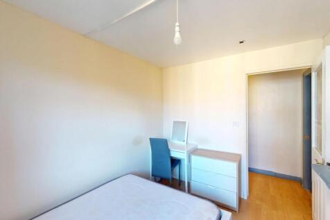 A bright and tidy bedroom featuring a bed, a sm...