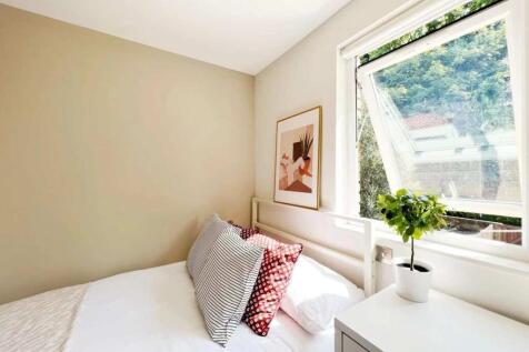 A bright and cozy bedroom featuring a white bed...