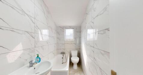 A sleek, modern bathroom featuring a white bath...