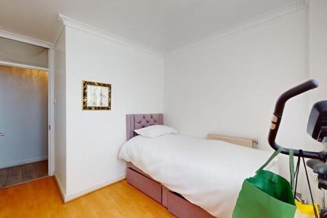 A tidy single bedroom featuring a neatly made b...