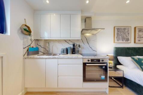 A modern studio space featuring a sleek white k...