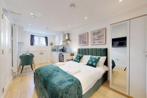 A stylish master bedroom featuring a plush gree...