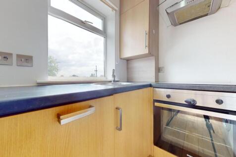 A modest kitchen with wooden cabinets and a bla...