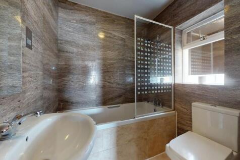 Modern bathroom featuring a bathtub with a glas...