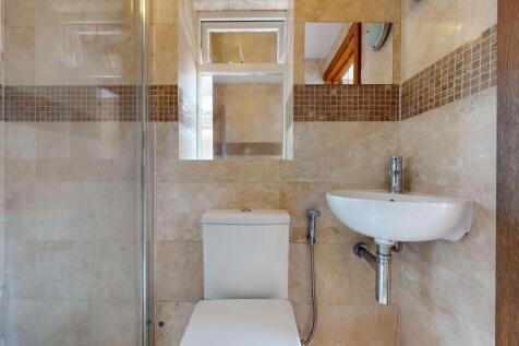 A modern, compact bathroom featuring a shower e...