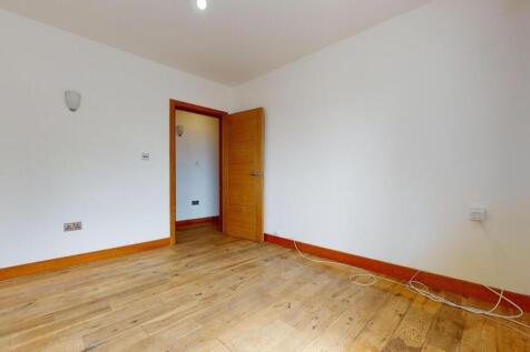 A bright, unfurnished bedroom with wooden floor...