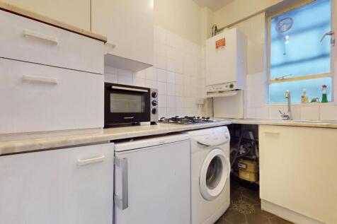 A compact kitchen featuring white cabinetry, a ...