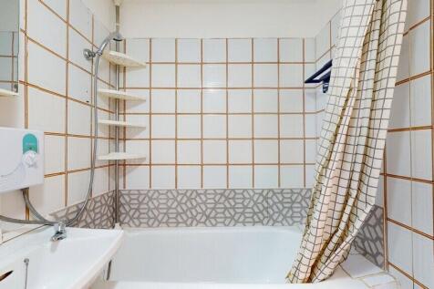 Bright and clean bathroom suite featuring a whi...