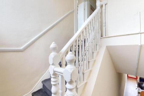 Bright and clean staircase with white wooden ba...