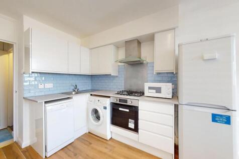 Bright modern kitchen with white cabinetry, pal...