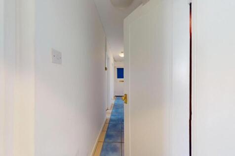 Bright narrow hallway with white walls, tiled f...
